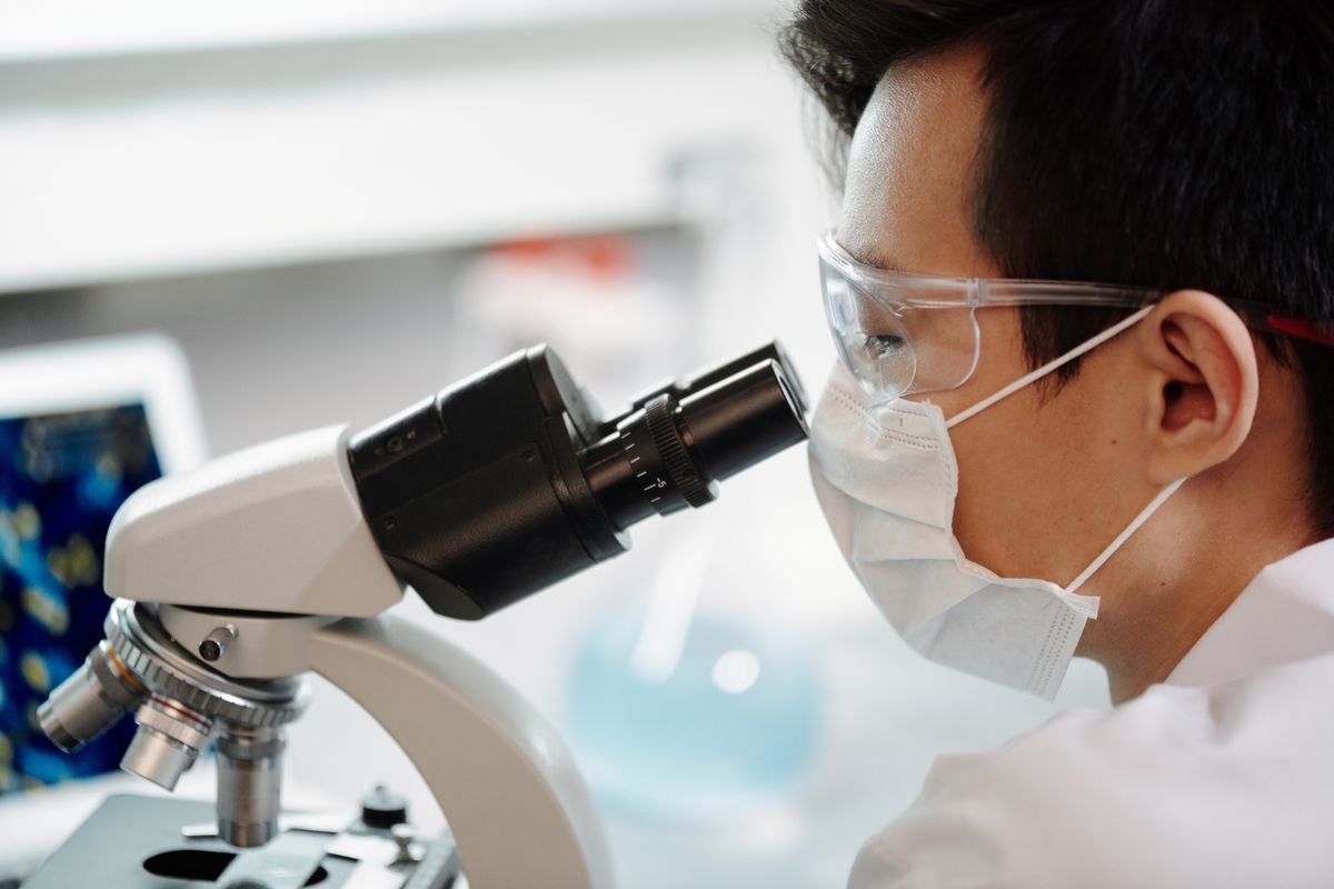 Illustrative stock photograph of a laboratory professional using a microscope